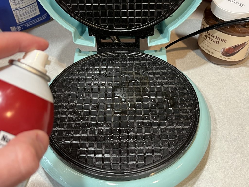 spraying down waffle iron