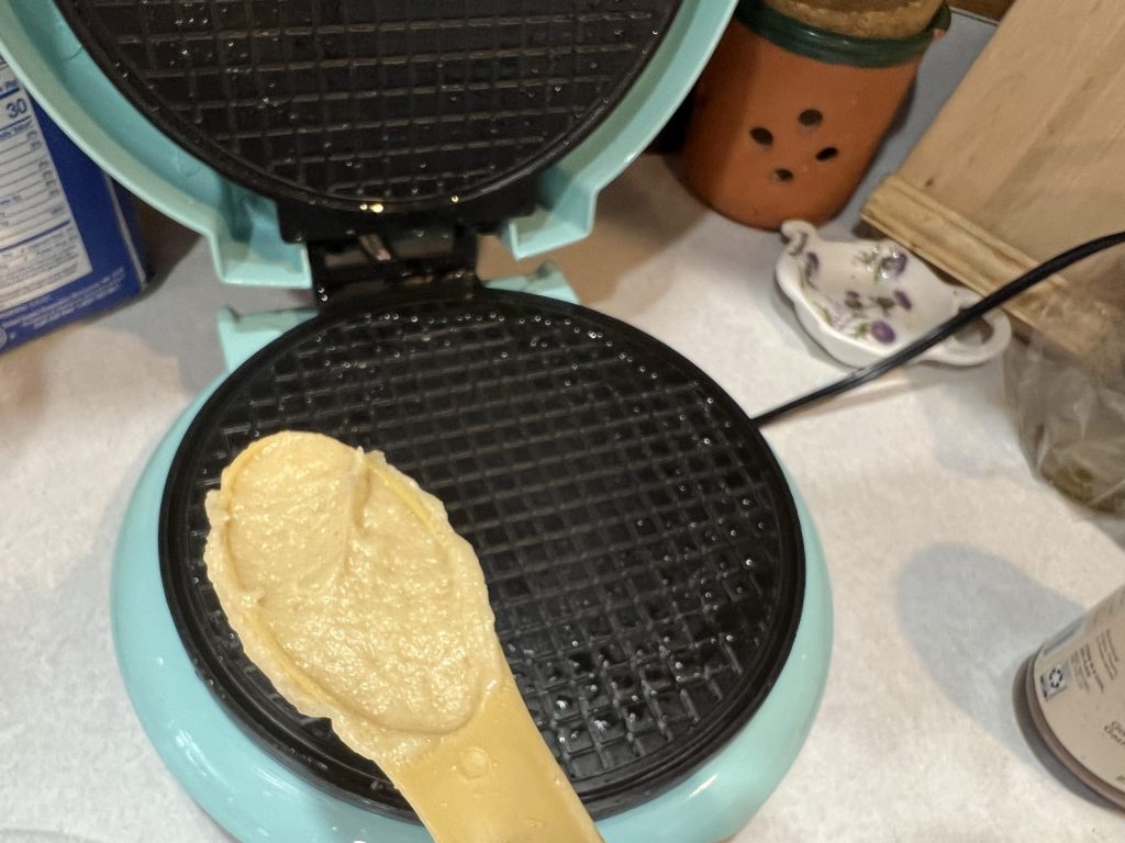putting dough on waffle iron for wafer cookies