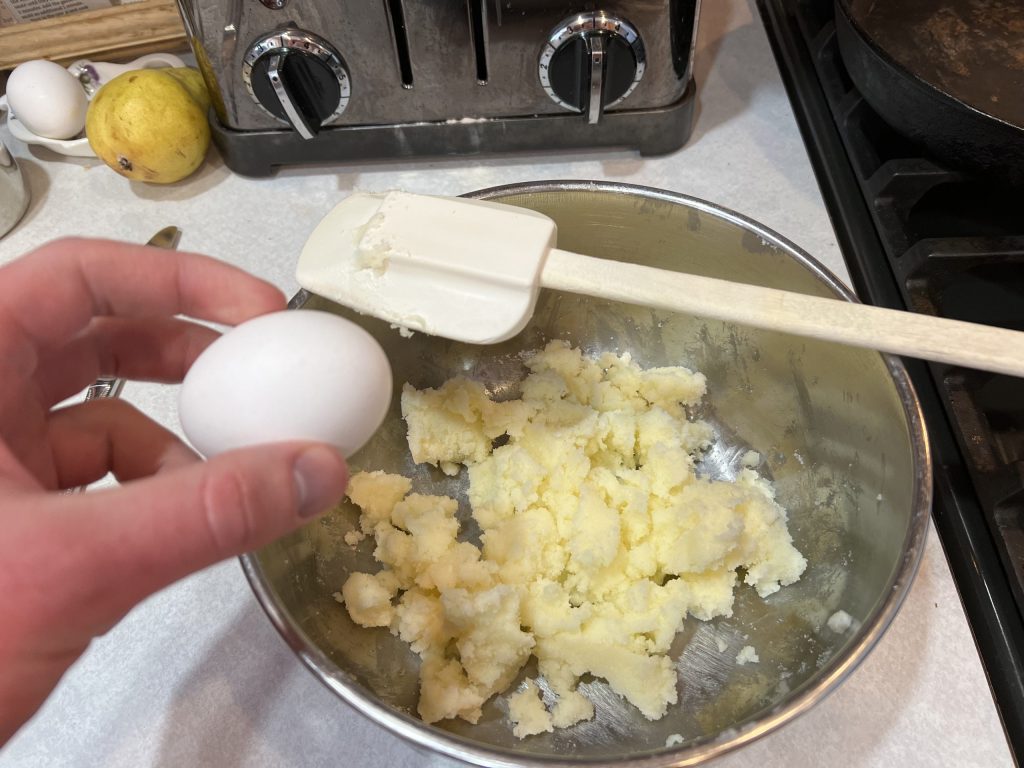 cracking egg into large bowl for banana bread recipe