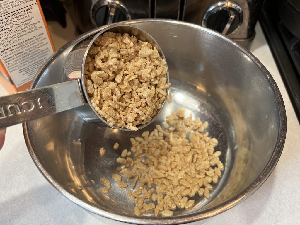 measuring out Rice Krispies for Rice Krispie Treat Recipe