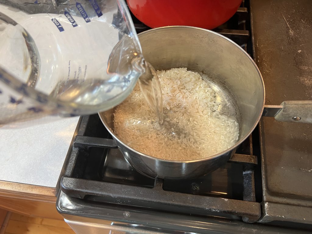 pouring water into saucepan with rice