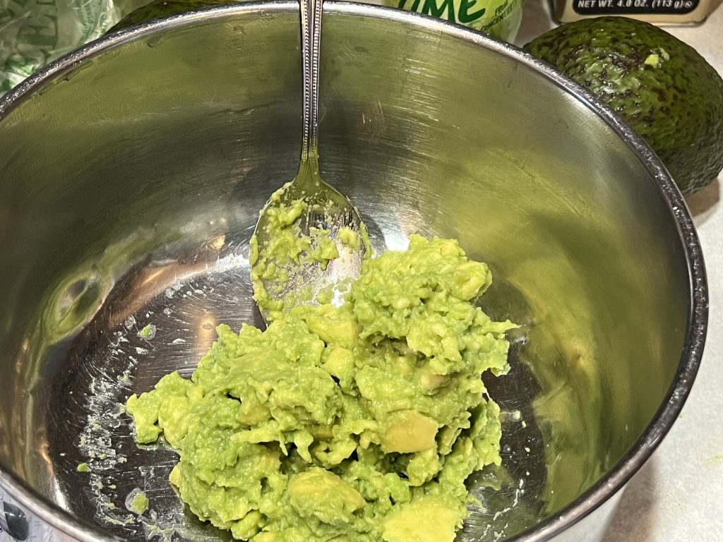 Mixing avocado around in a large bowl for a guacamole recipe