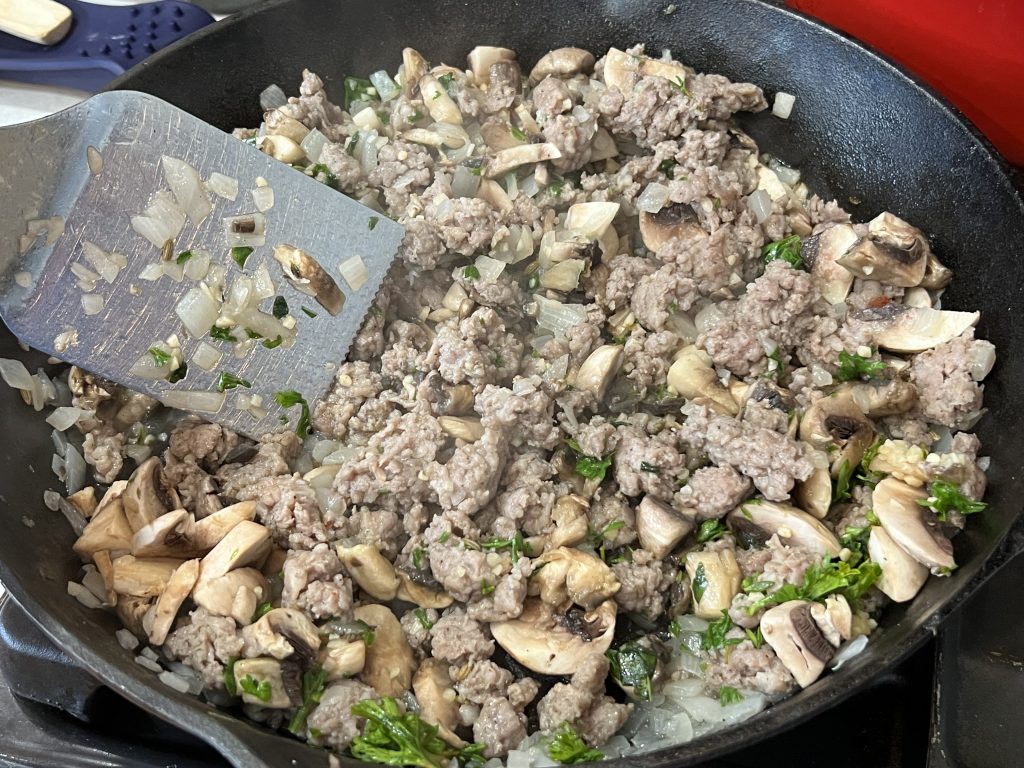 cooking meat and other ingredients in a skillet