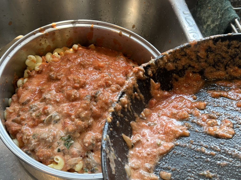mixing pasta sauce with noodles