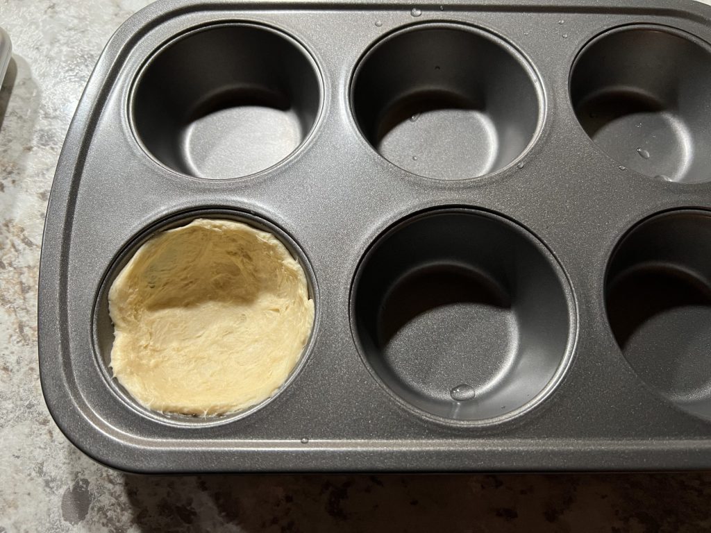 Muffin tin with dough in it.