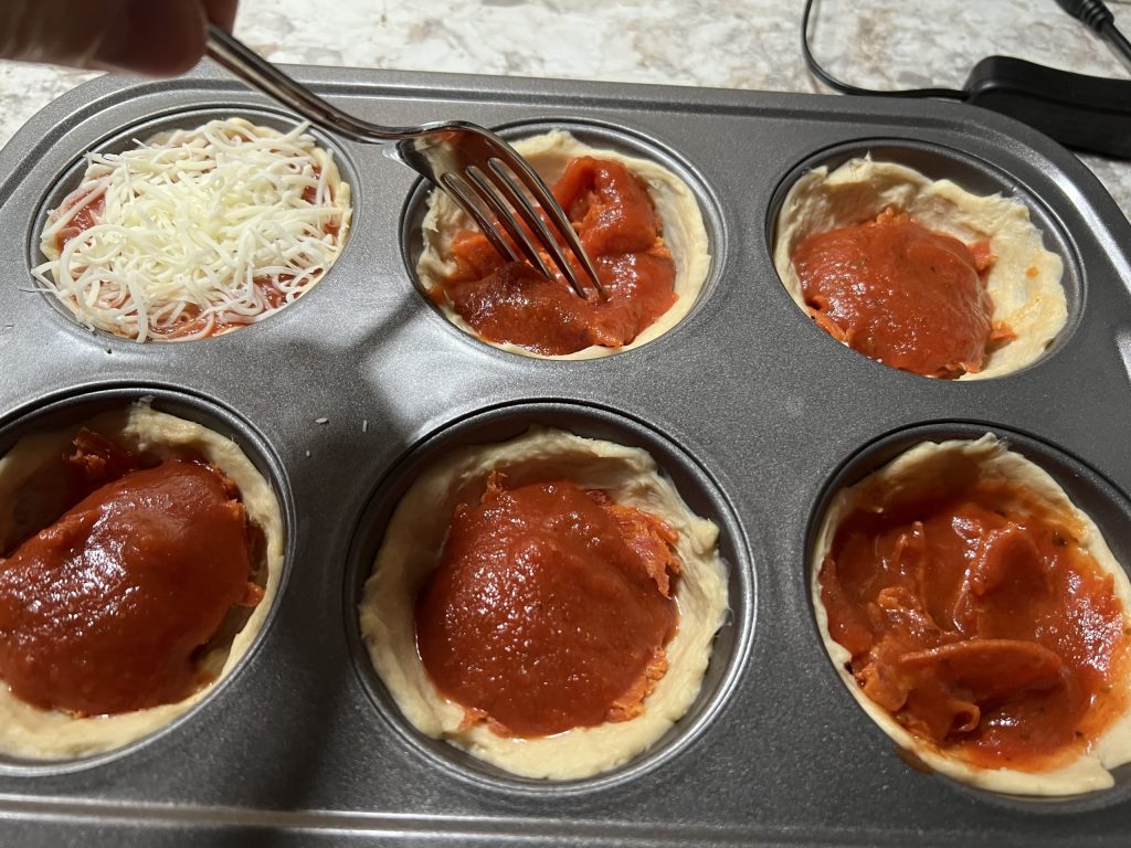 muffin cups with pizza cupcake ingredients in them.