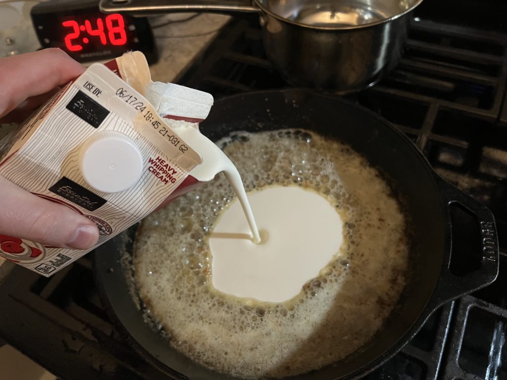 pouring heavy cream into skillet for chicken alfredo recipe