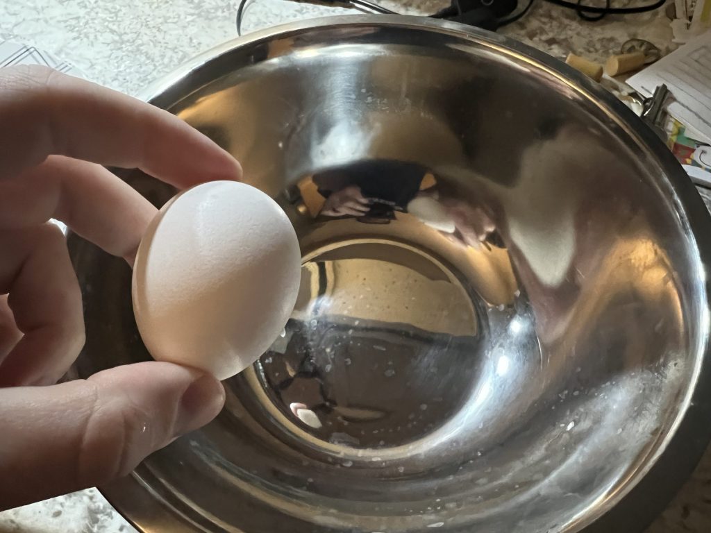 cracking two eggs into a medium mixing bowl for chicken parmesan recipe